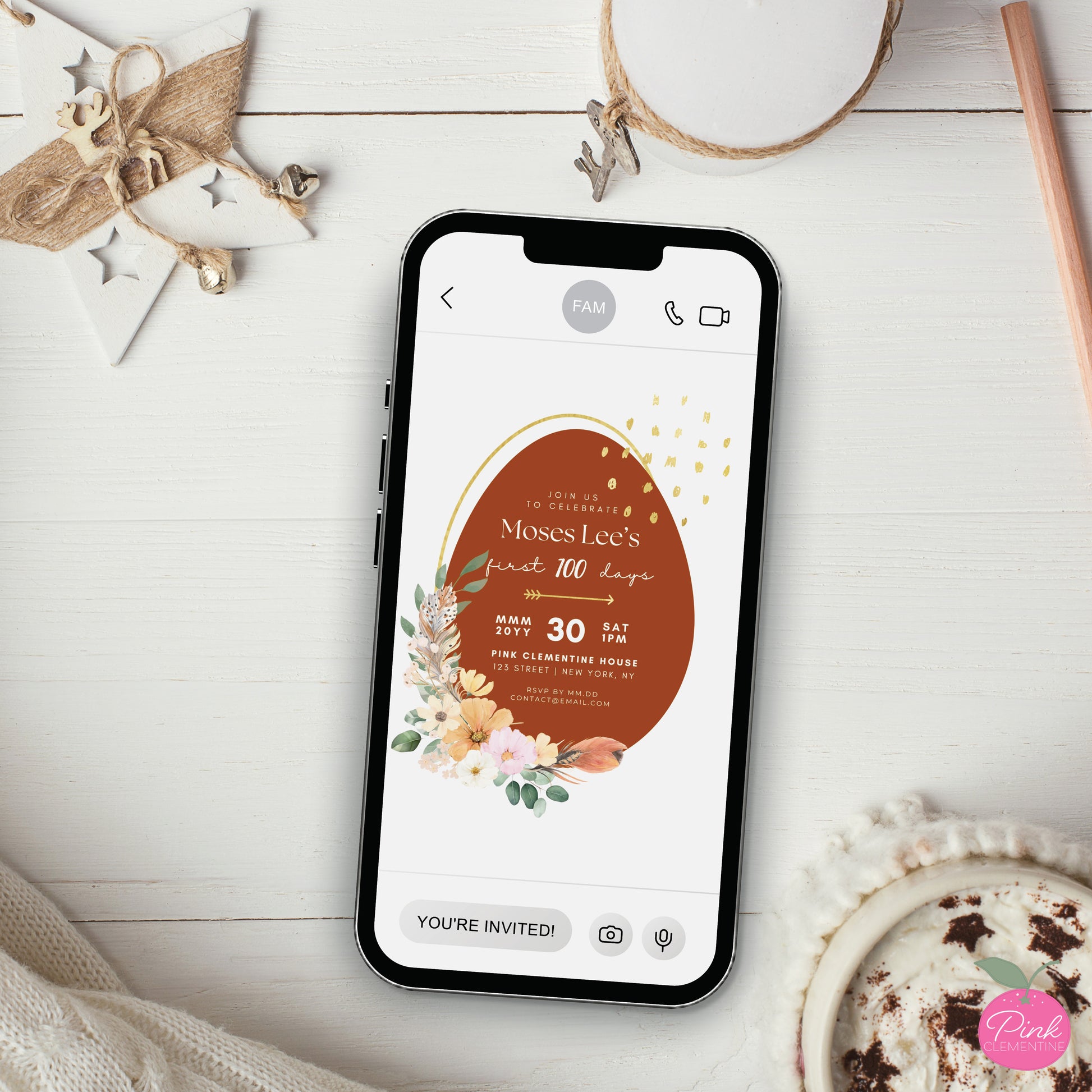 Red egg and ginger baby shower editable invitation template displayed on a phone. Design features large red egg with boho style flower and feathers.